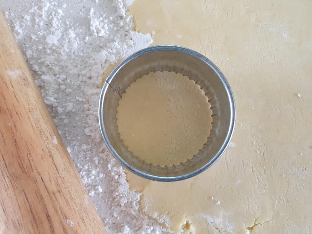 Gluten free shortbread 13 top down view view cutting out dough with round, crimped cookie cutter, with rolling pin on the side.