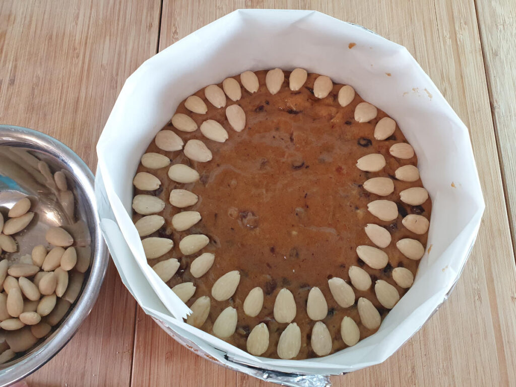 decorating cake with blanched almonds in a circular pattern.