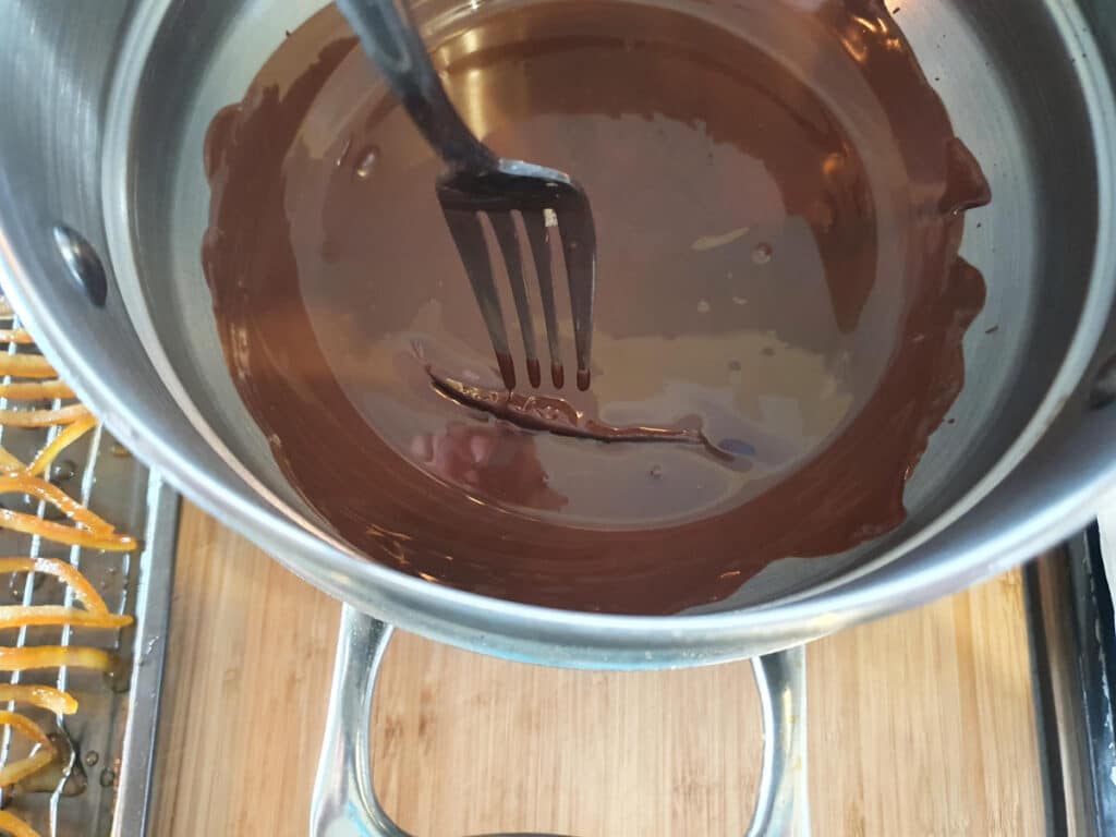 flipping peel in melted chocolate over with a fork to fully coat.