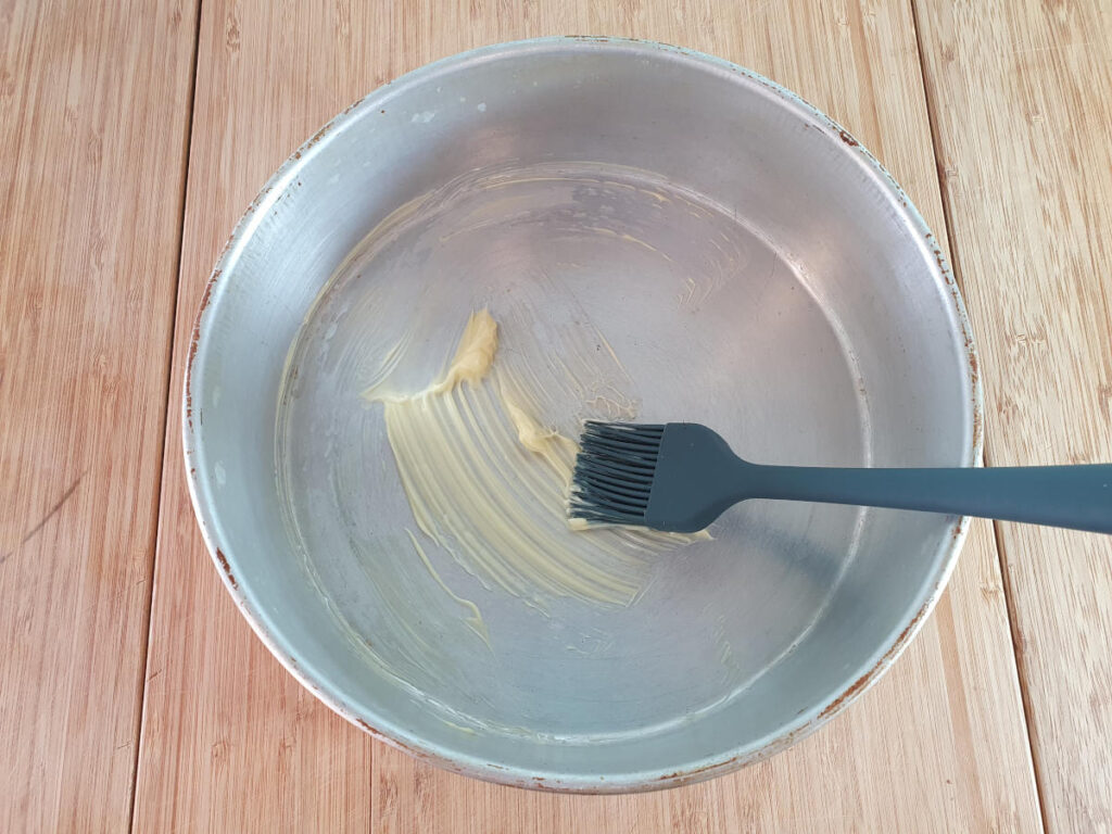 greasing cake tin with butter and a pastry brush.