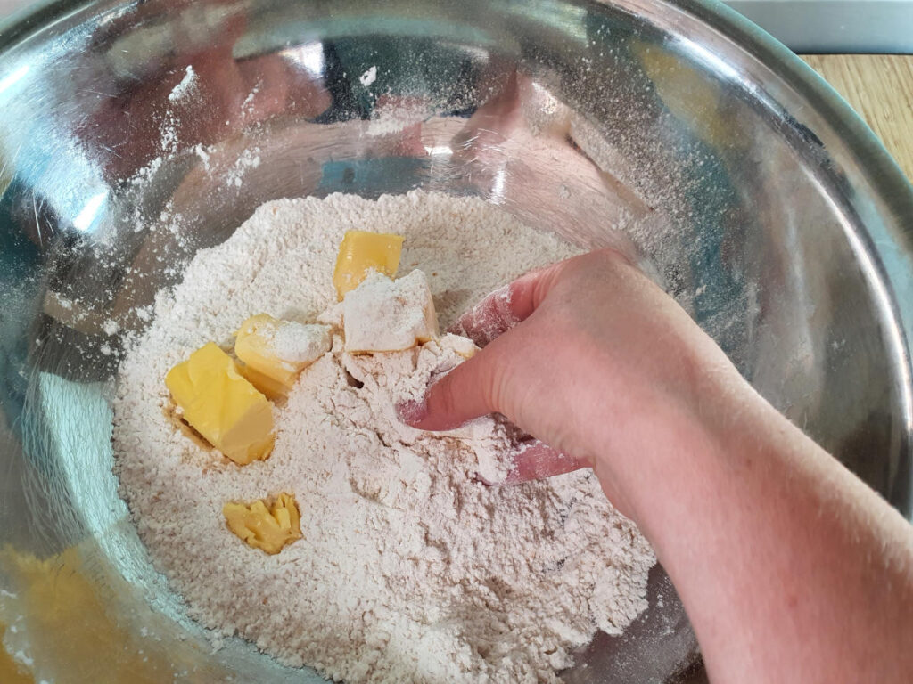 rubbing butter into the dry ingredients with hands.