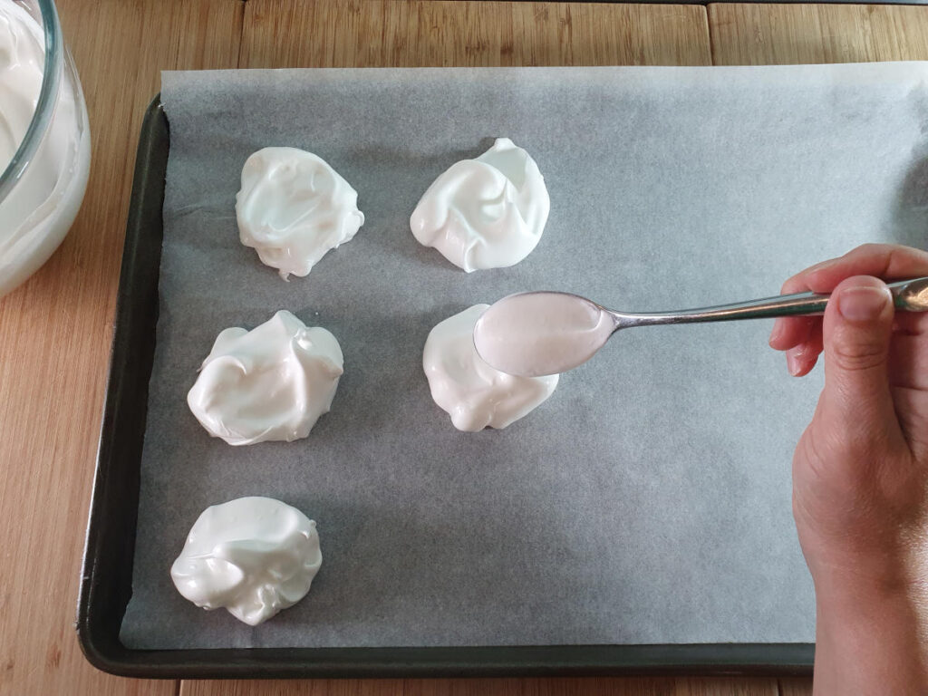 spooning meringue mix onto tray lined with baking paper.