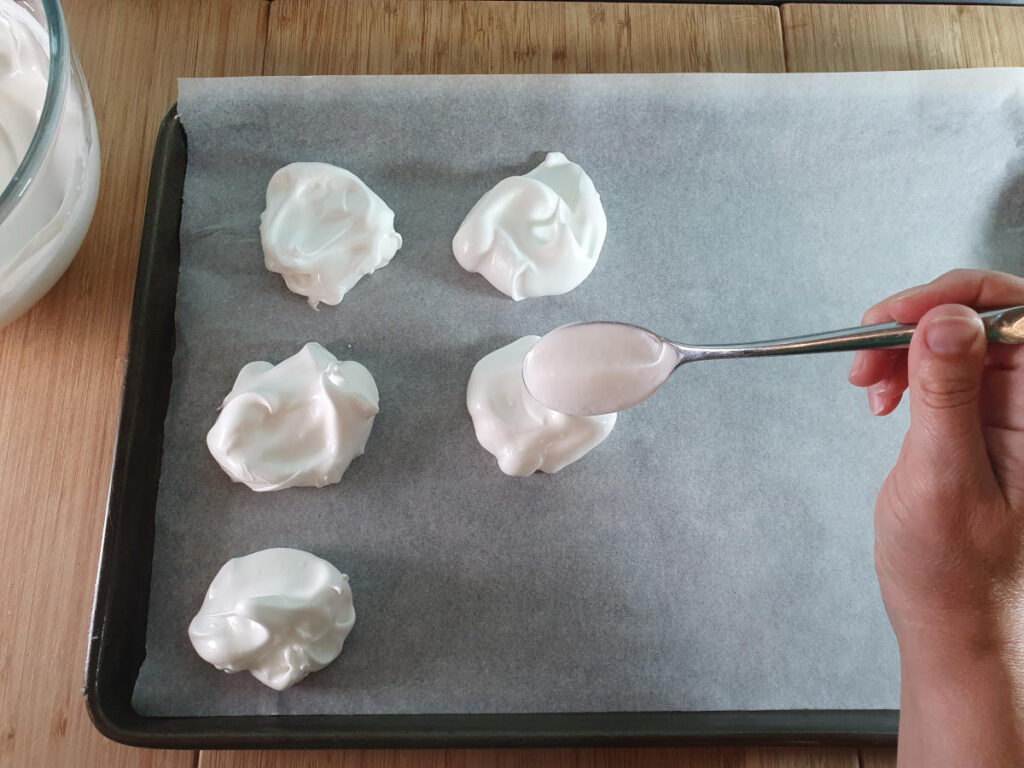 Eton mess 8 spooning meringue mix onto tray lined with baking paper.