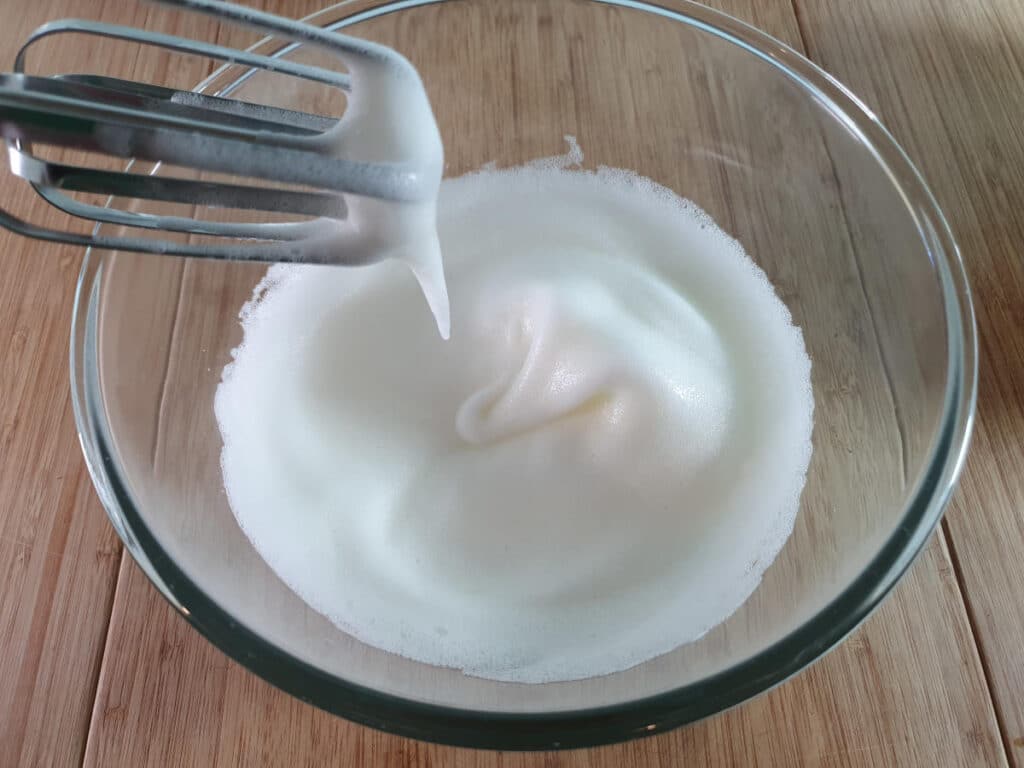 whipping egg whites to soft white peaks.