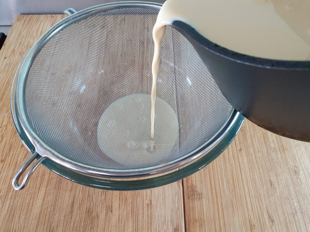 Straining ice cream mix with a strainer into a bowl.