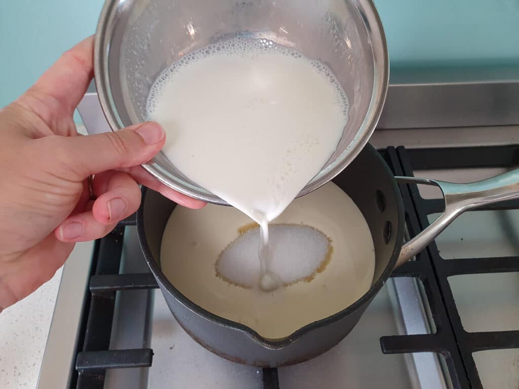 Adding gelatin and milk to pot on stove.