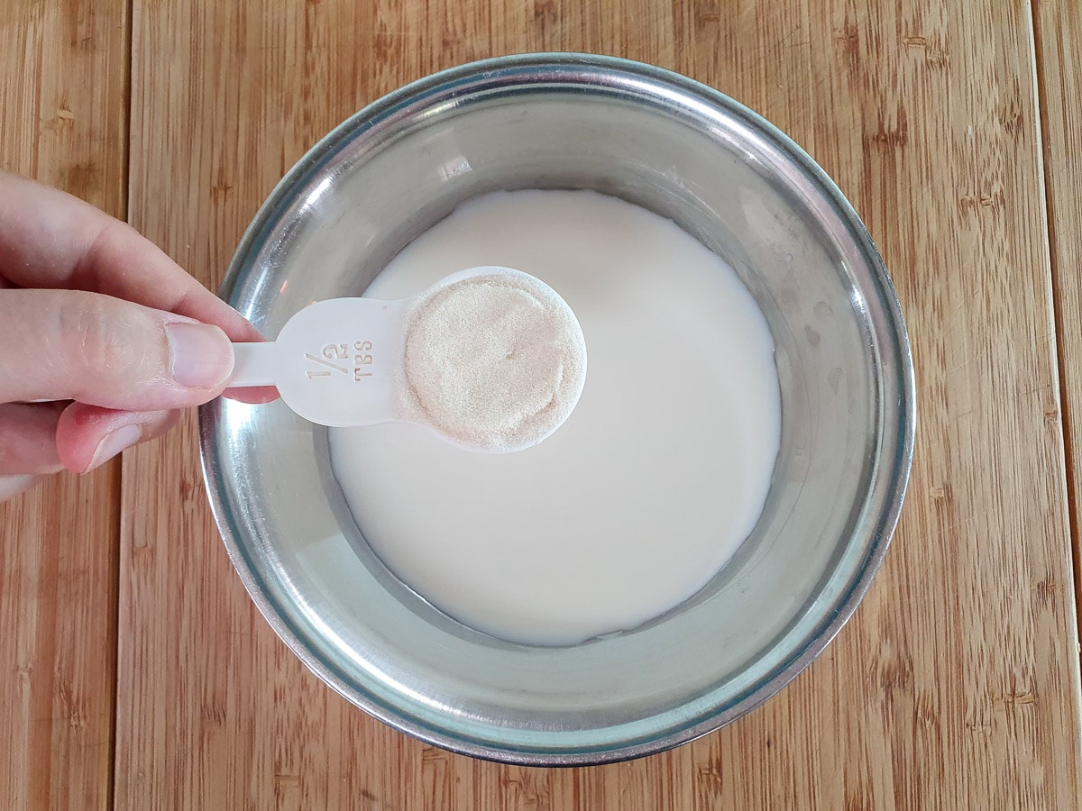 Sprinkling gelatin over milk into a bowl.