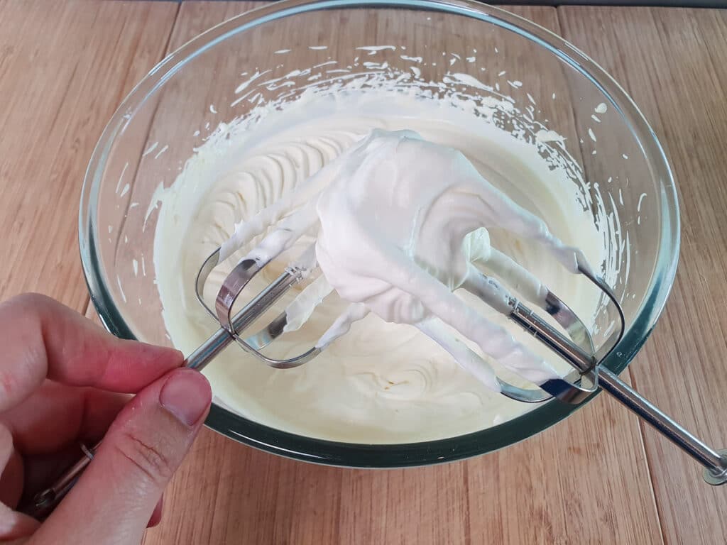 Tapping beaters against each other to remove cream, so as not to nock the air out of the whipped cream in a bowl.
