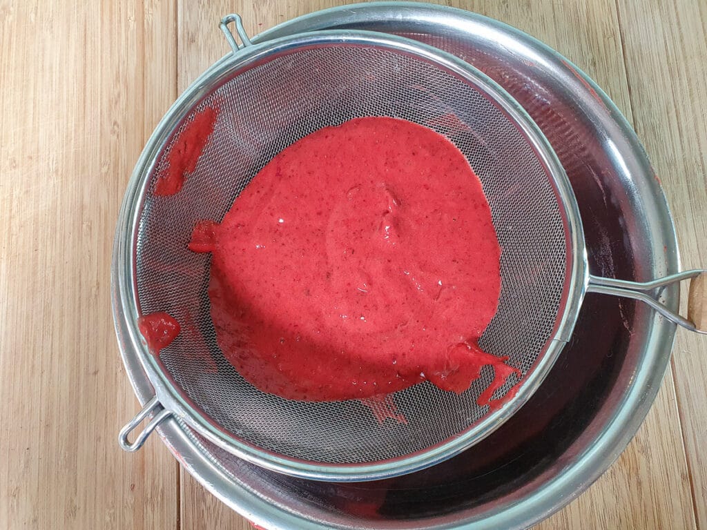 Straining blitzed strawberry pulp.