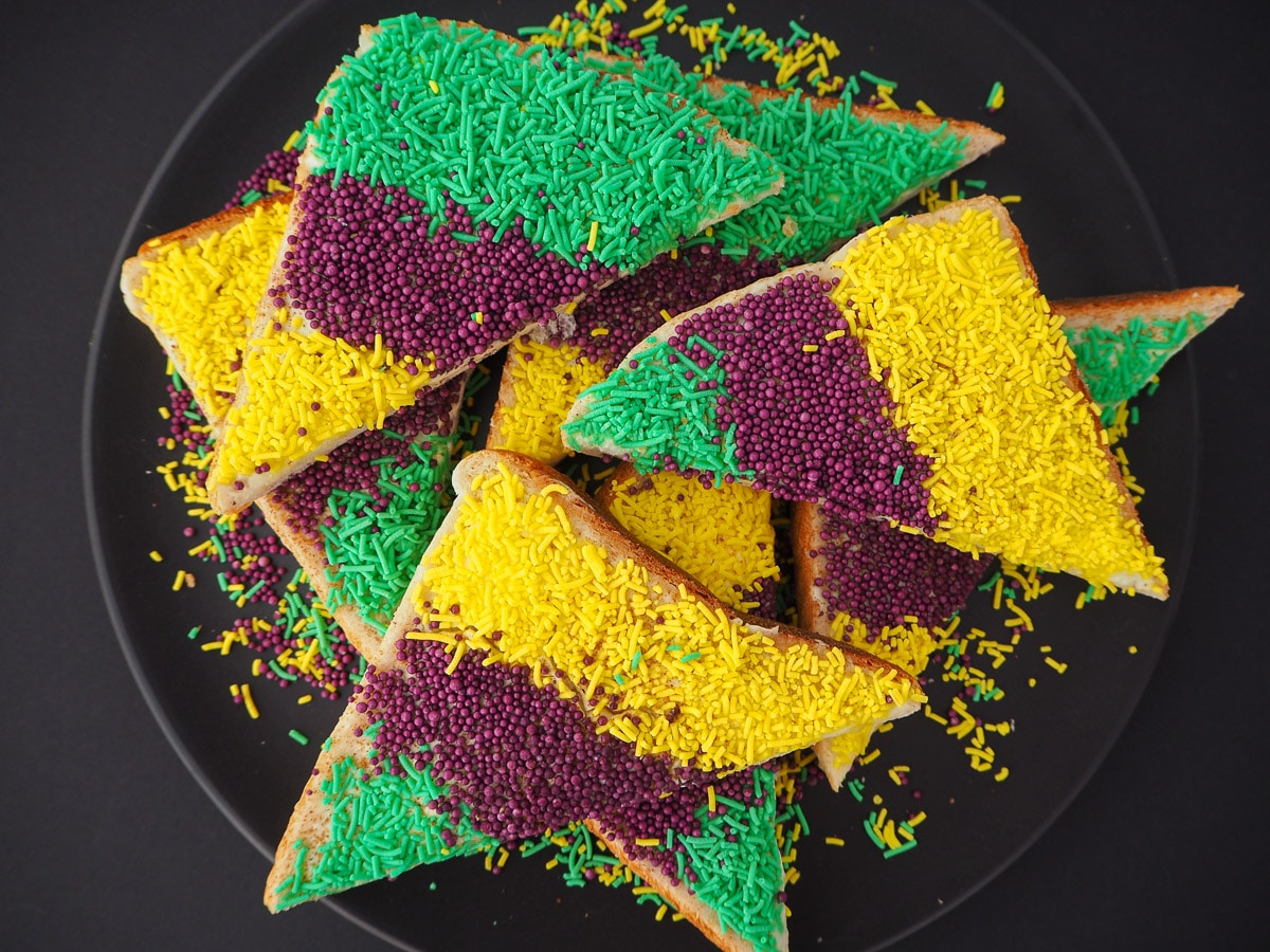 King cake sprinkles bread 9 Slices of King cake sprinkles bread on a black plate.