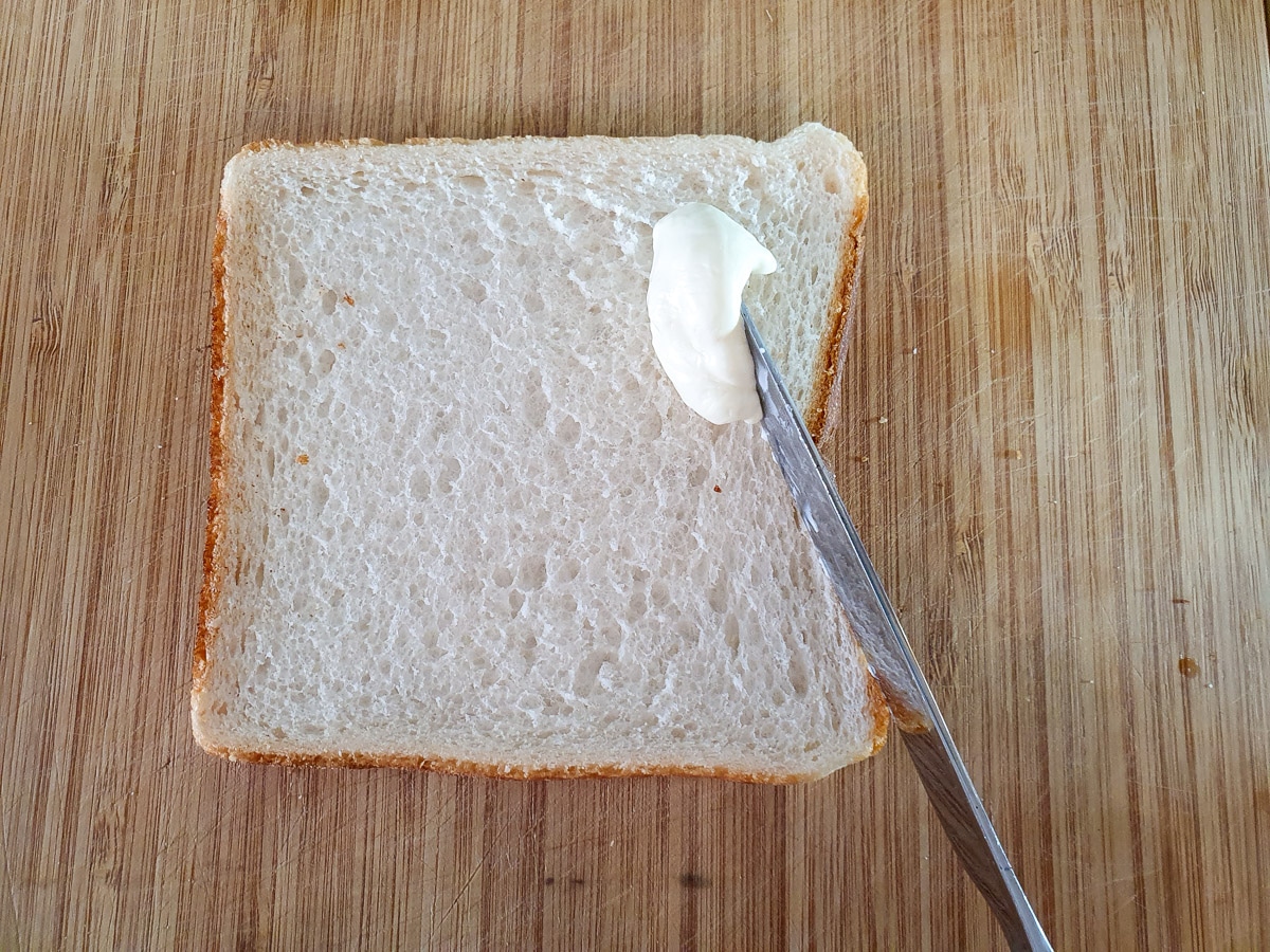 Spreading softened cream cheese over bread.