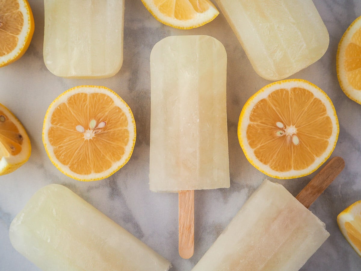 Lemonade popsicles surrounded by fresh lemon slices.