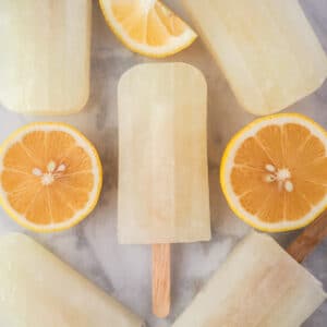Close up of lemonade popsicles surrounded by fresh lemon slices.