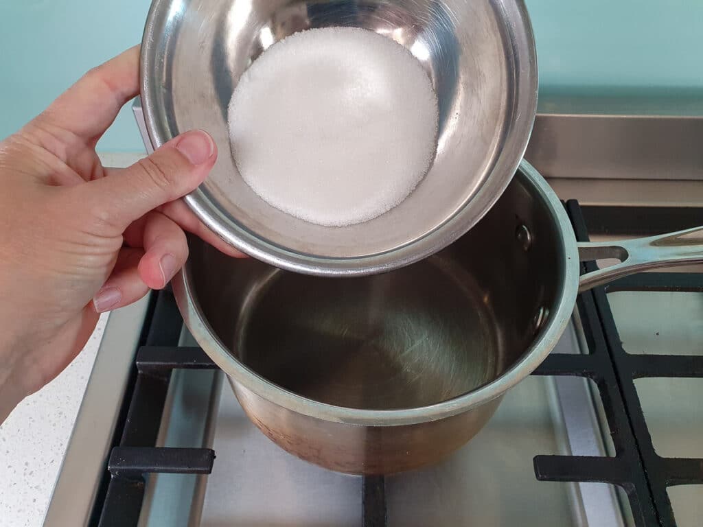 adding sugar to pot on stove.