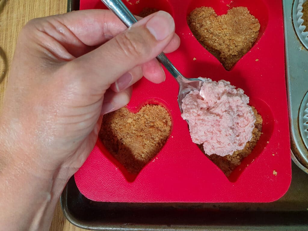 Mini strawberry cheesecake 18 Spooning filling into molds.