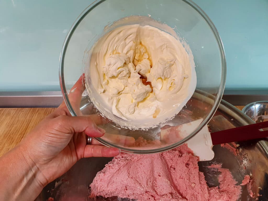 Adding whipped cream into strawberry mix.