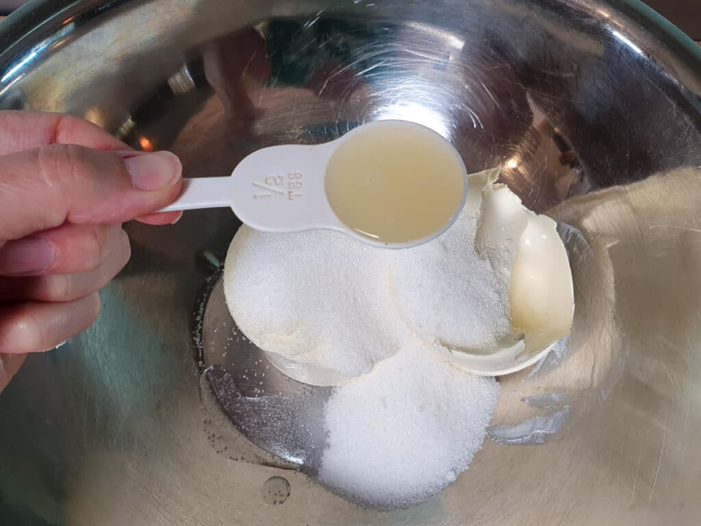 Adding lemon juice to sugar and cream cheese.