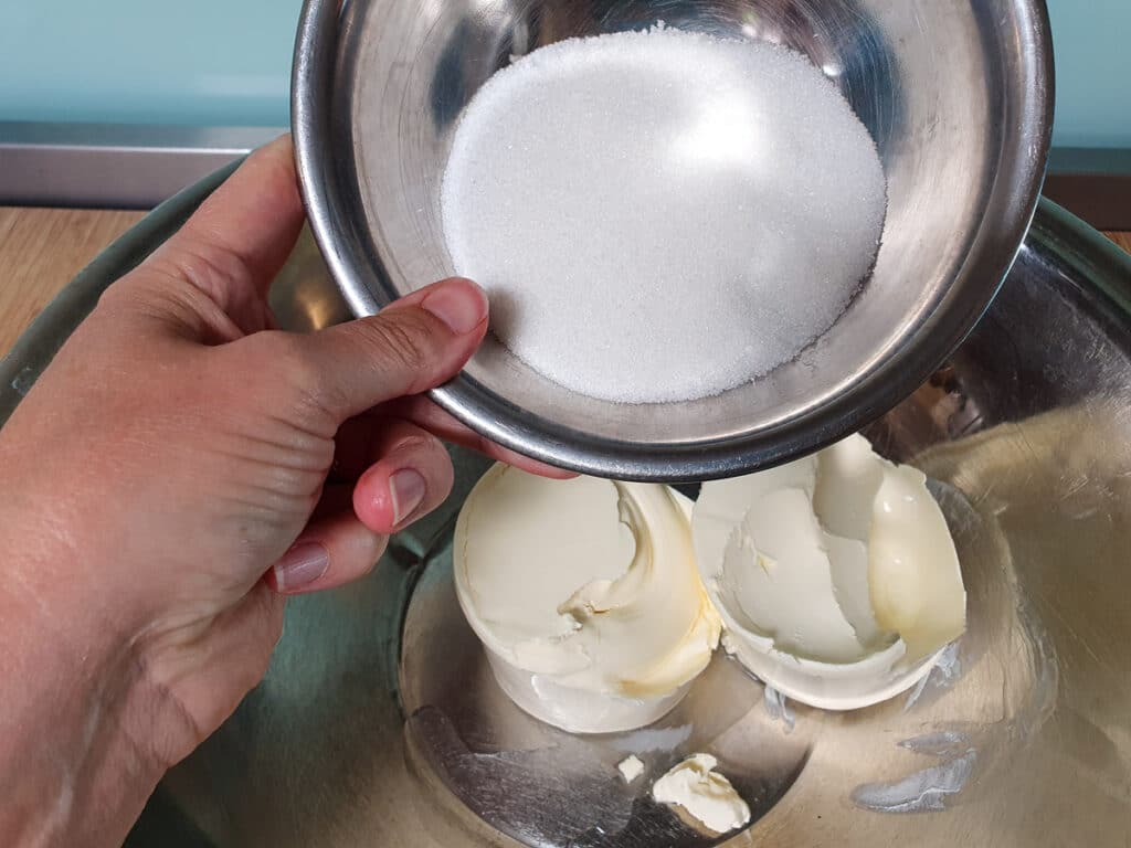 Adding sugar to cream cheese.