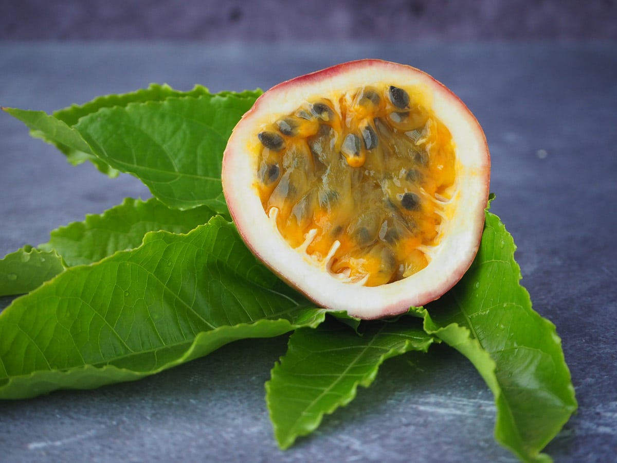 Fresh passion fruit cut in half with passion fruit leaves.