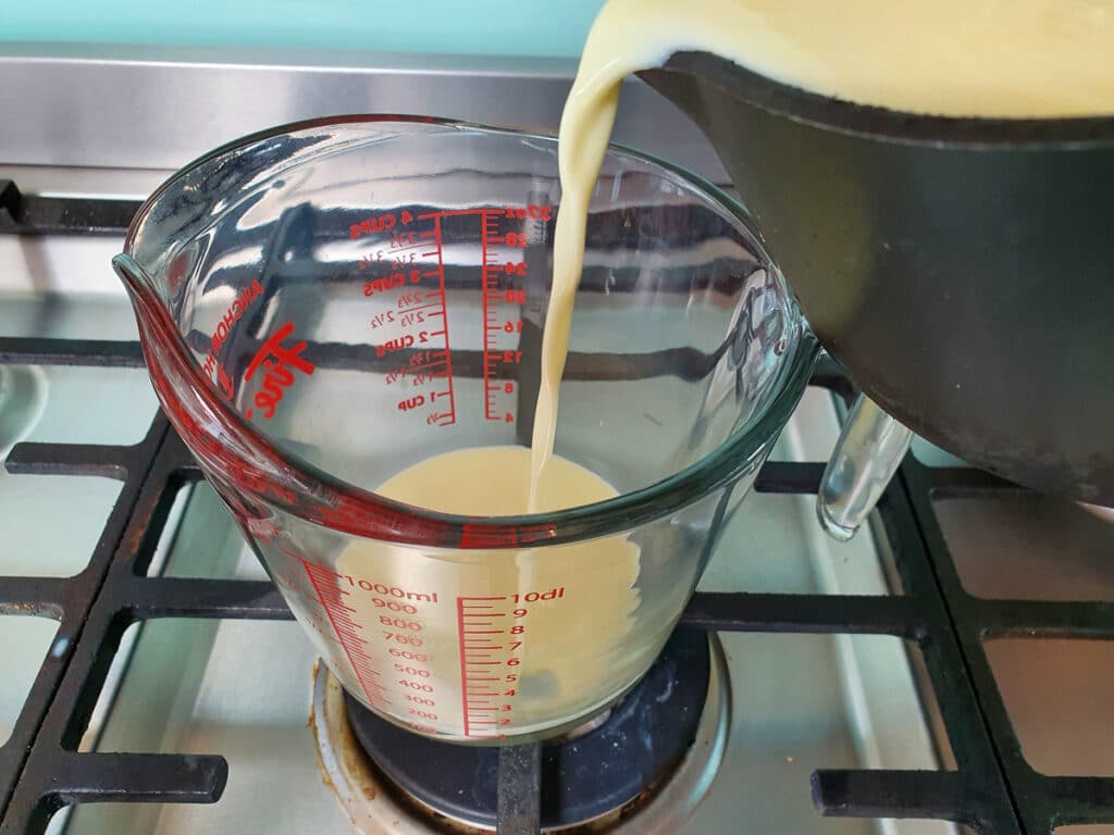 Pouring ice cream base into a jug to cool.