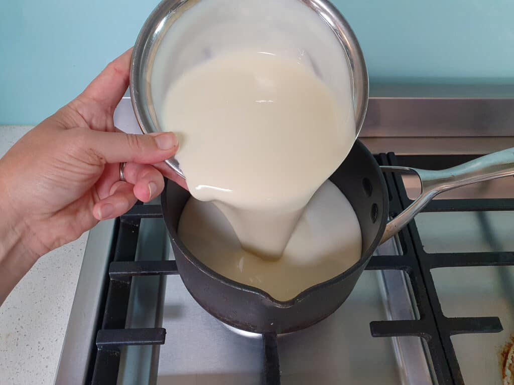 Adding cream to pot on stove.
