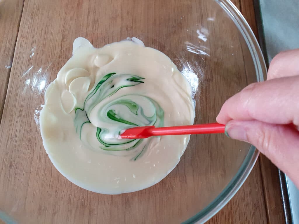 Stirring green food color into melted white chocolate.