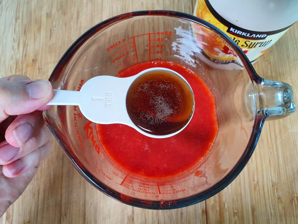 Adding maple syrup to blitzed strawberries.