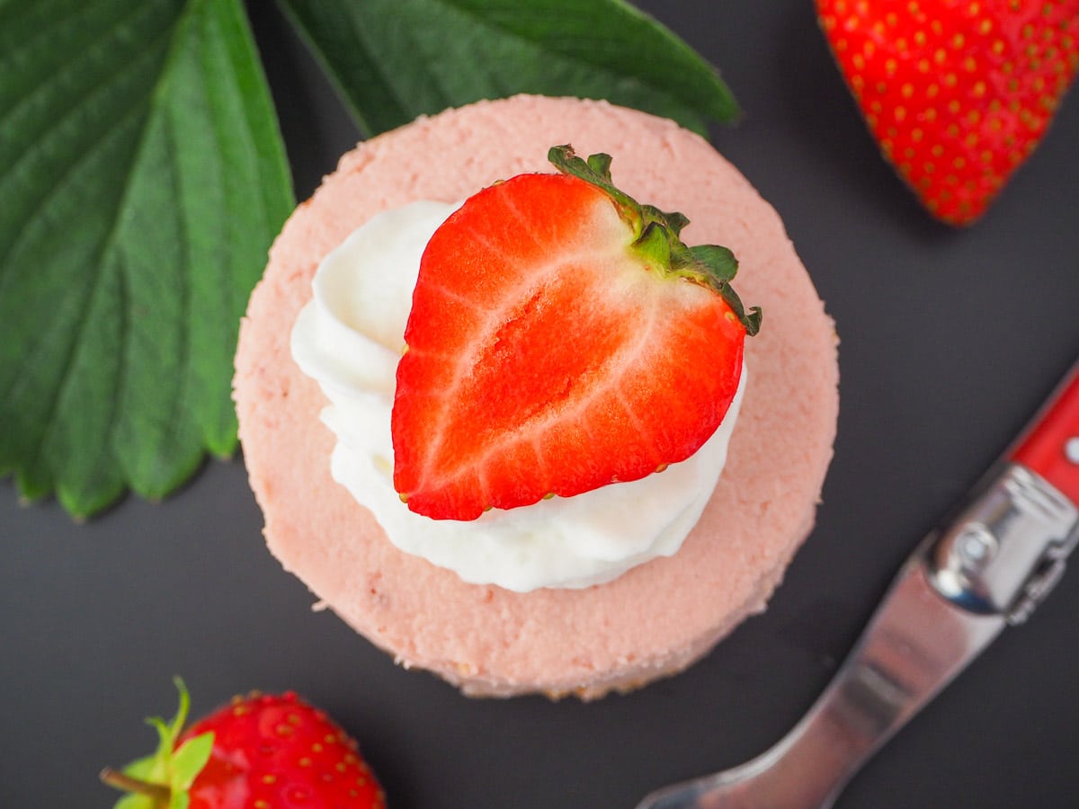Mini strawberry cheesecake 23 Round mini strawberry cheesecake with whipped cream, fresh strawberries, fresh strawberry leaves and a vintage fork.