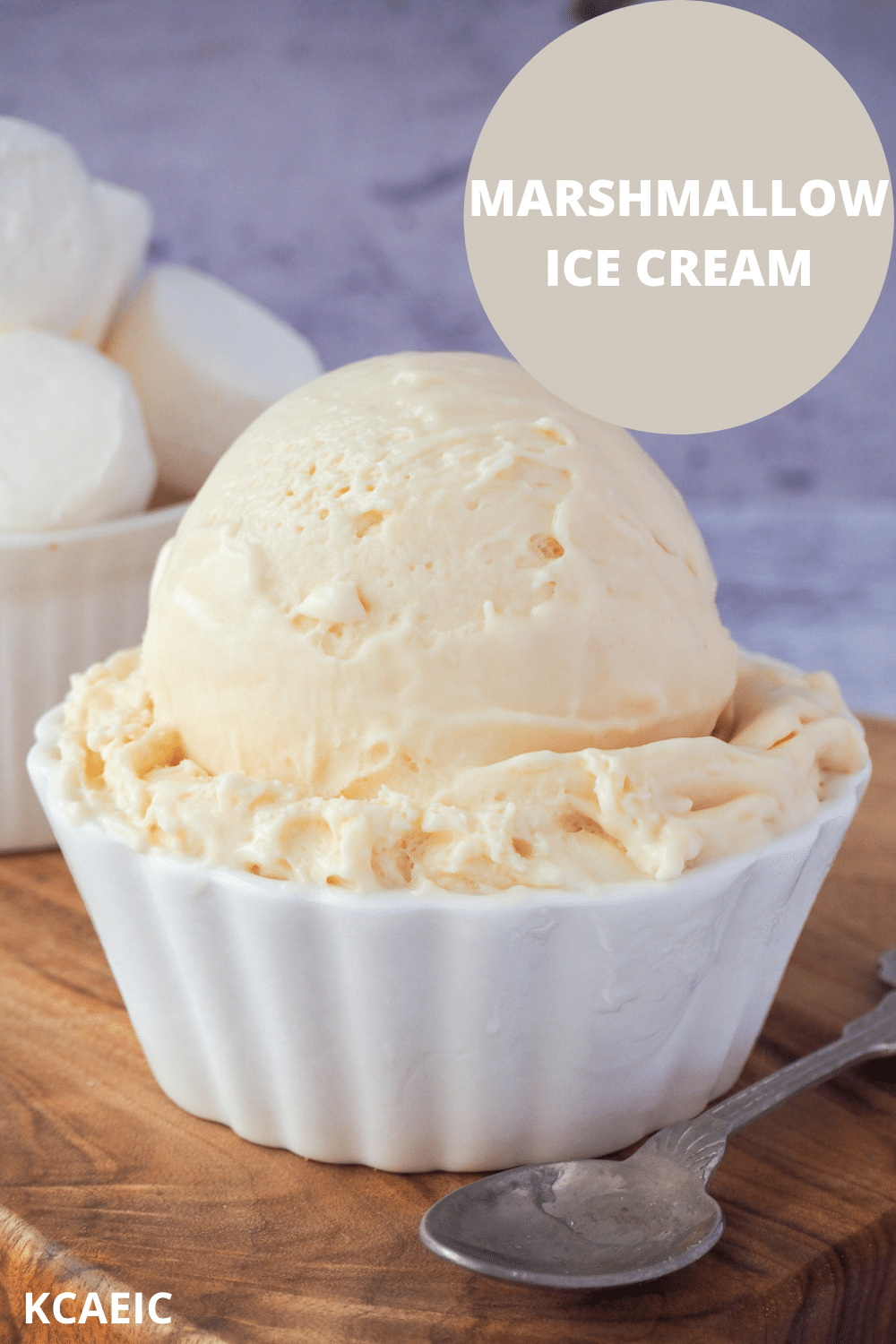 Scoop of marshmallow ice cream in a decorative white bowl, with vintage spoon on the side, bowl of marshmallows in the background and text overlay, marshmallow ice cream, KCAEIC.