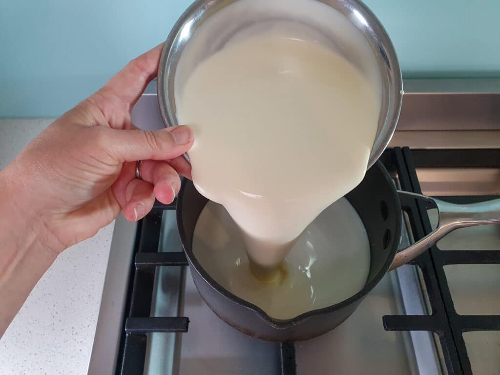 Adding cream to pot on stove.