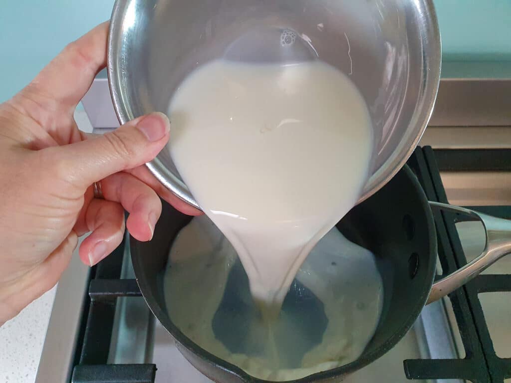 Adding milk to pot on stove.