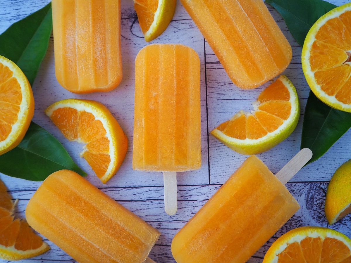 Orange popsicles with fresh orange and orange leaves.