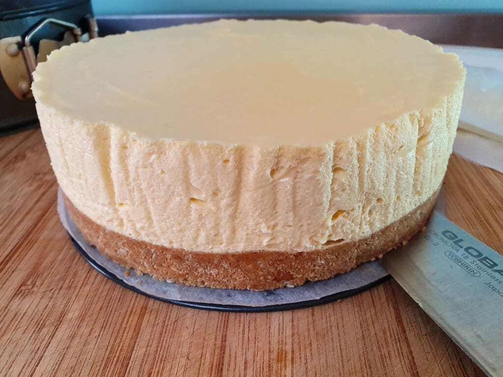 Passion fruit cheesecake 20 Sliding cheesecake off bottom of cake tin with a large knife.