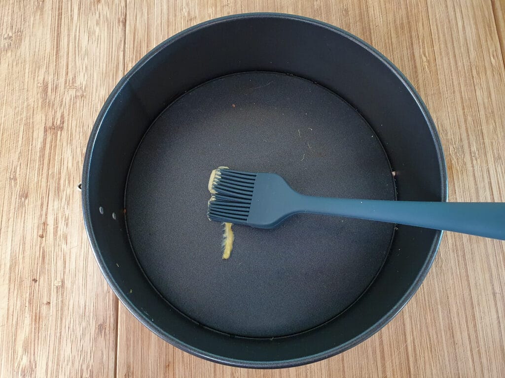 Greasing springform tin before lining with baking paper.