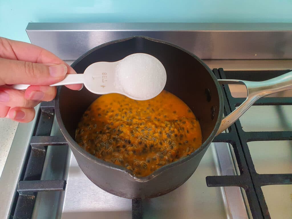 Adding sugar to pot on stove.