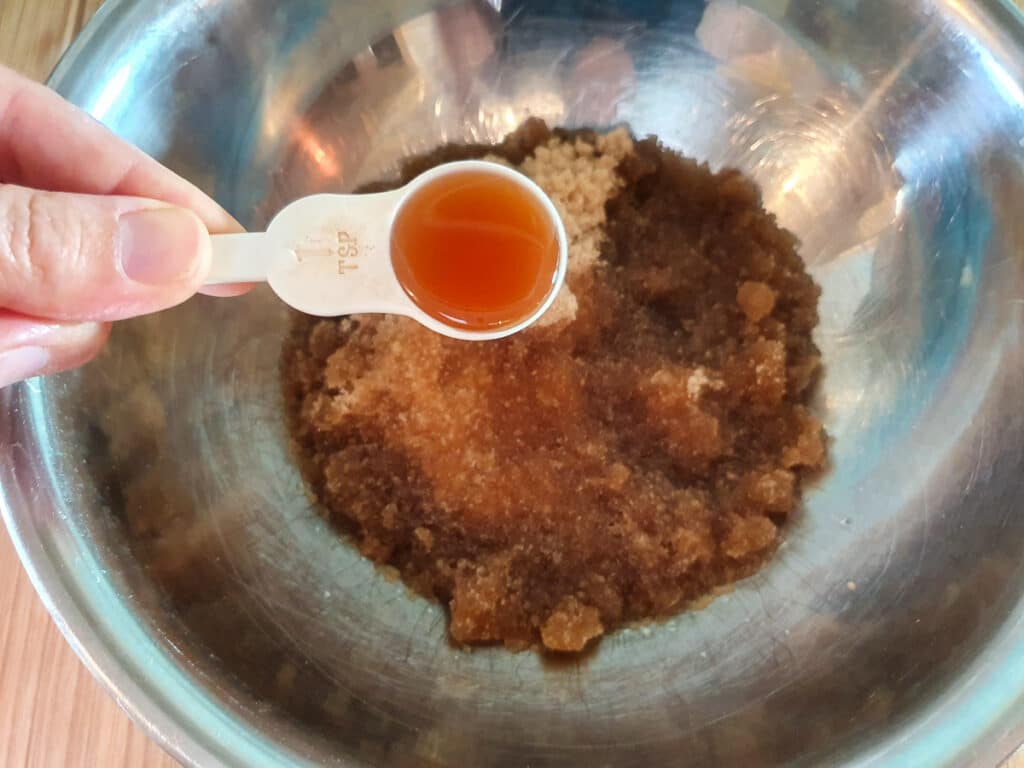 Adding vanilla essence to sugar and oil mix.