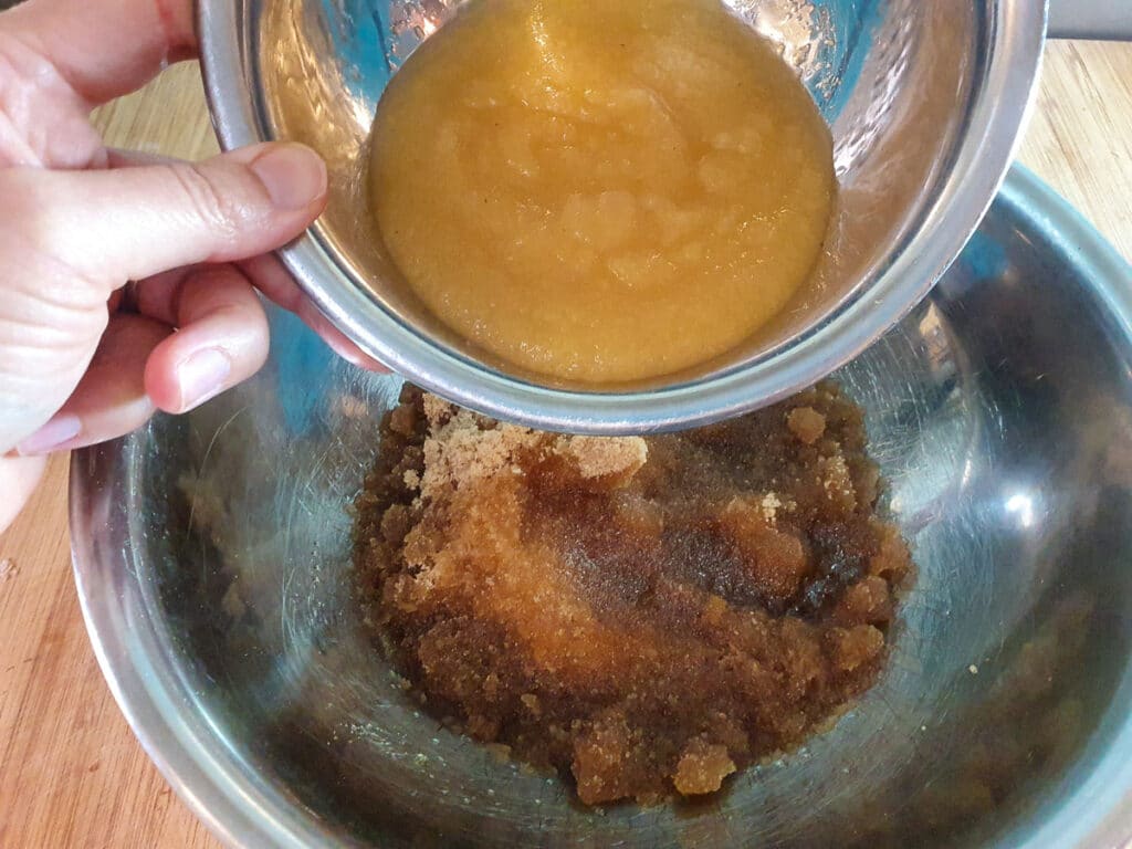 Adding apple sauce to sugar and oil mix.