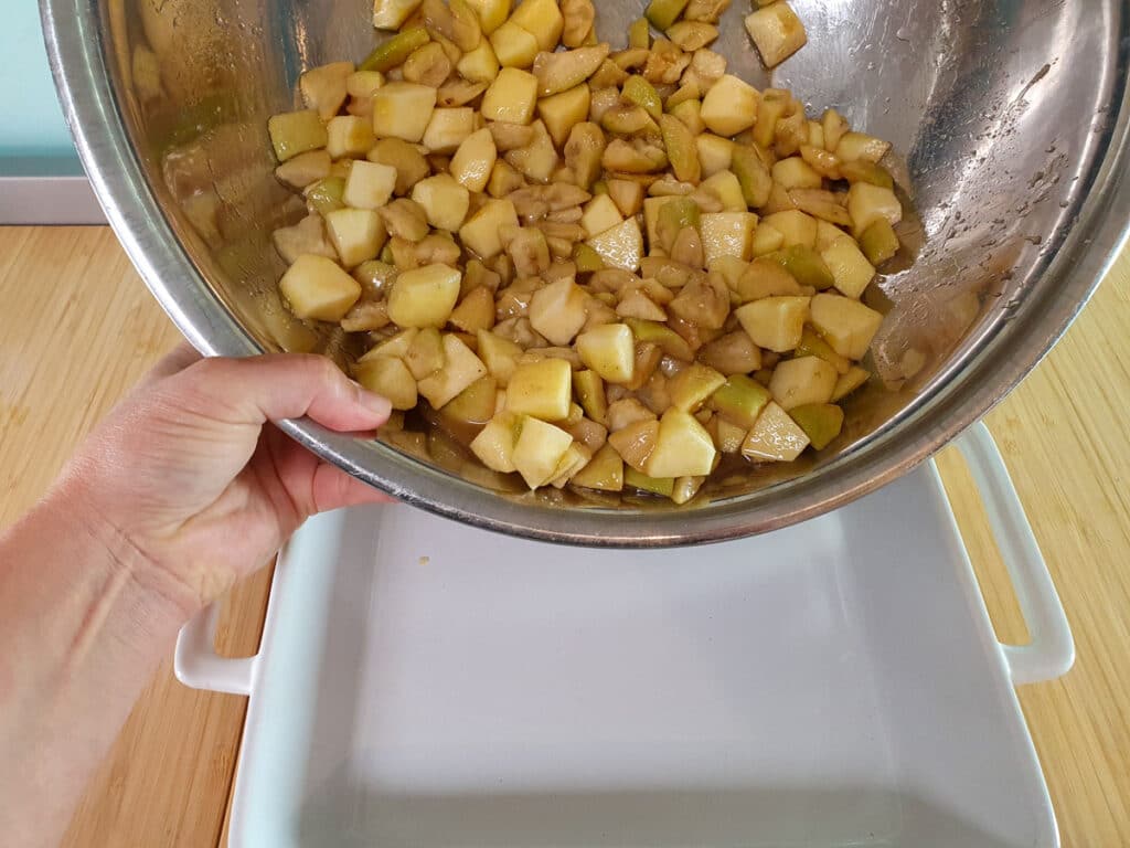 Tipping fruit mix into baking dish.