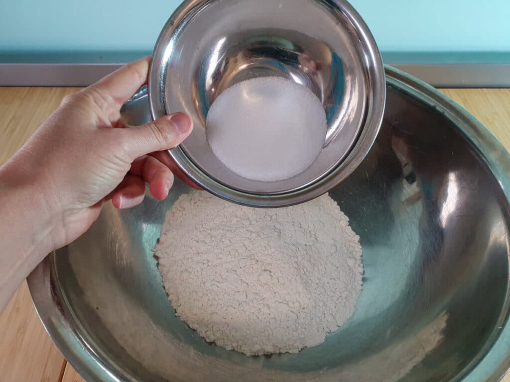 Adding sugar to flour.