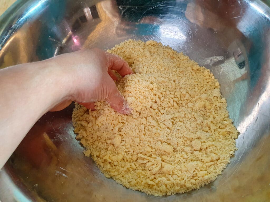 Rubbing butter in to flour and sugar mix with clean hands.