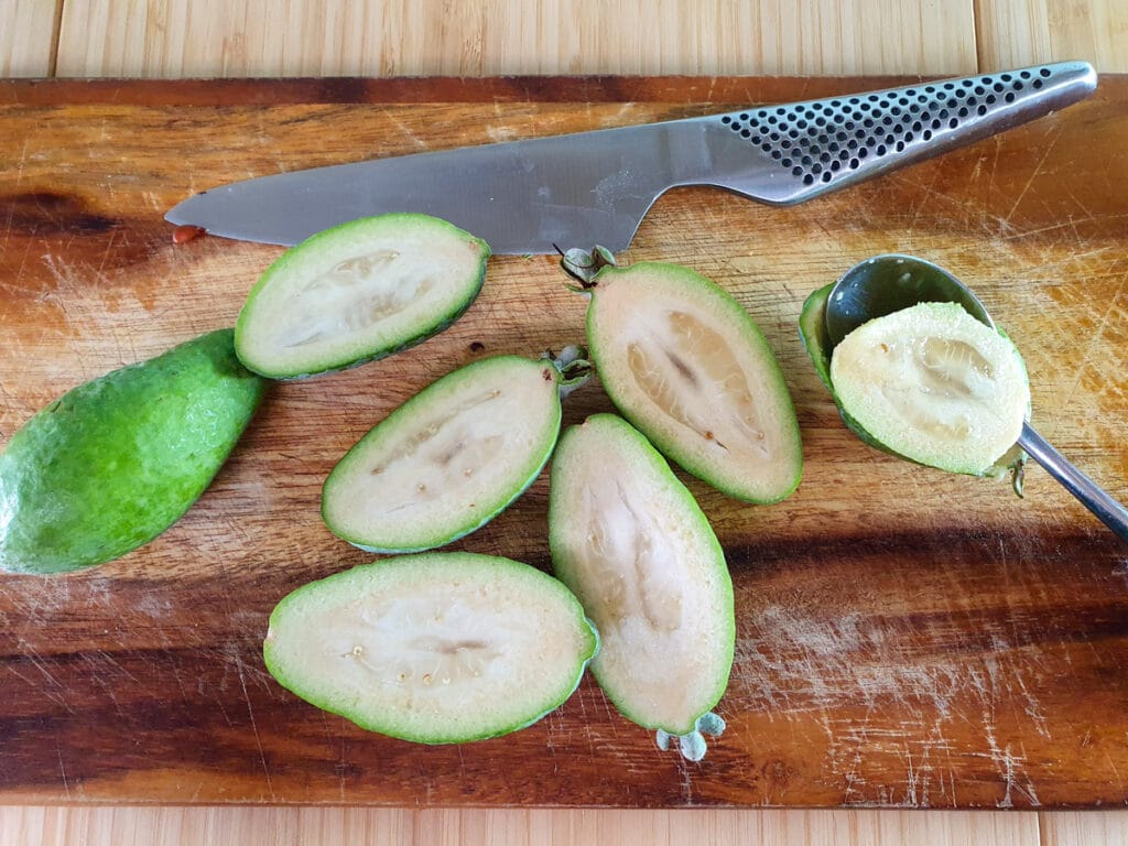 Cutting open feijoas lengthways and scooping out flesh with a teaspoon.