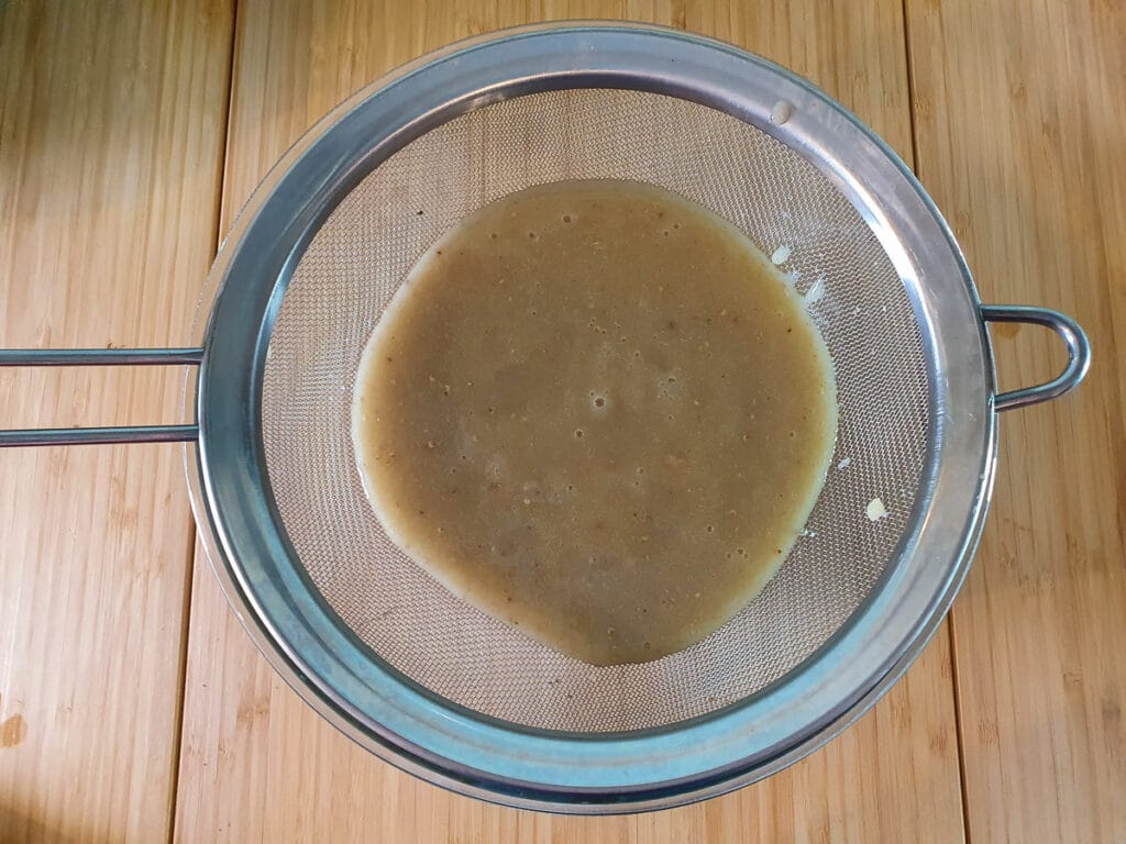 Straining blitzed feijoa pulp.