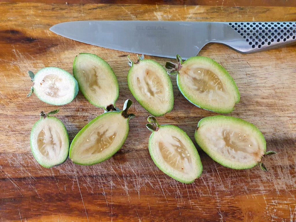 Slicing feijoas length ways to scoop out flesh.