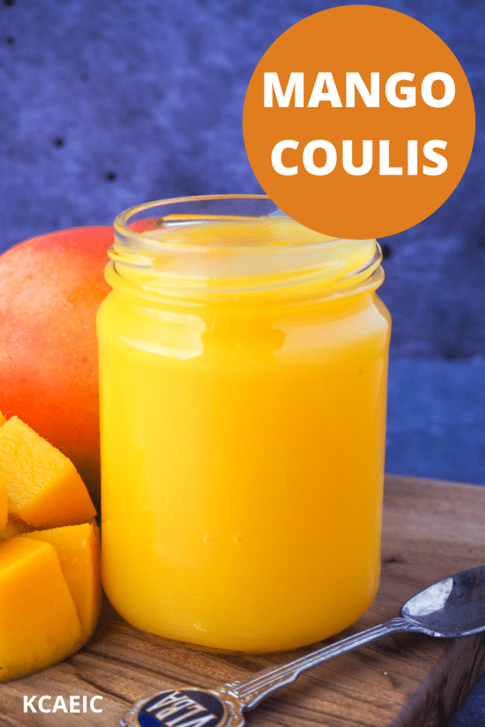 Open glass jar of mango coulis with fresh mango and a vintage spoon on the side, with text overlay, mango coulis and KCAEIC.