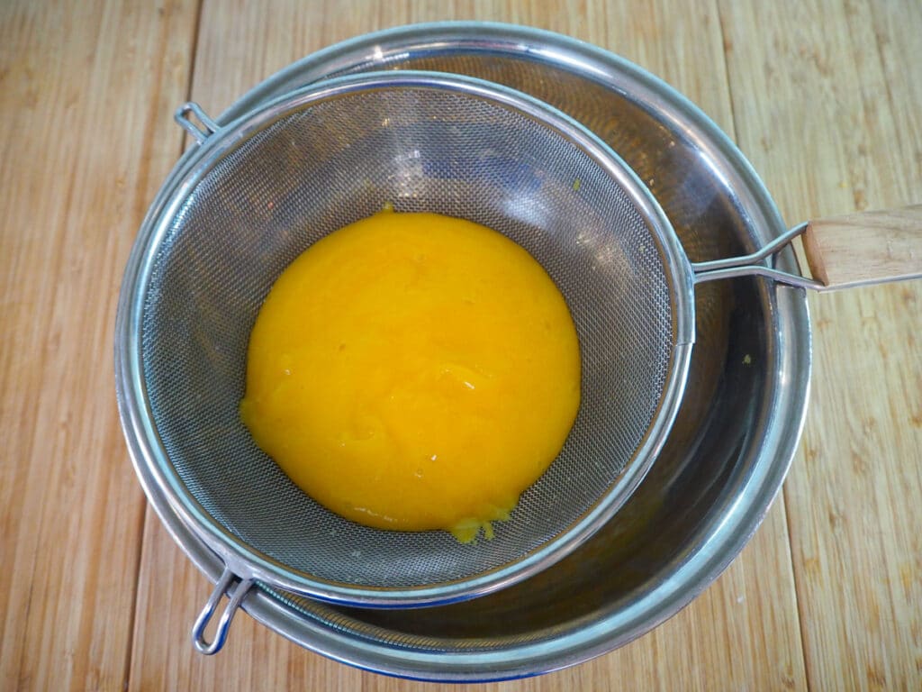 Straining the blitzed mango.