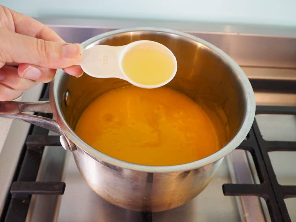 Adding lime juice to mango mix in pot.