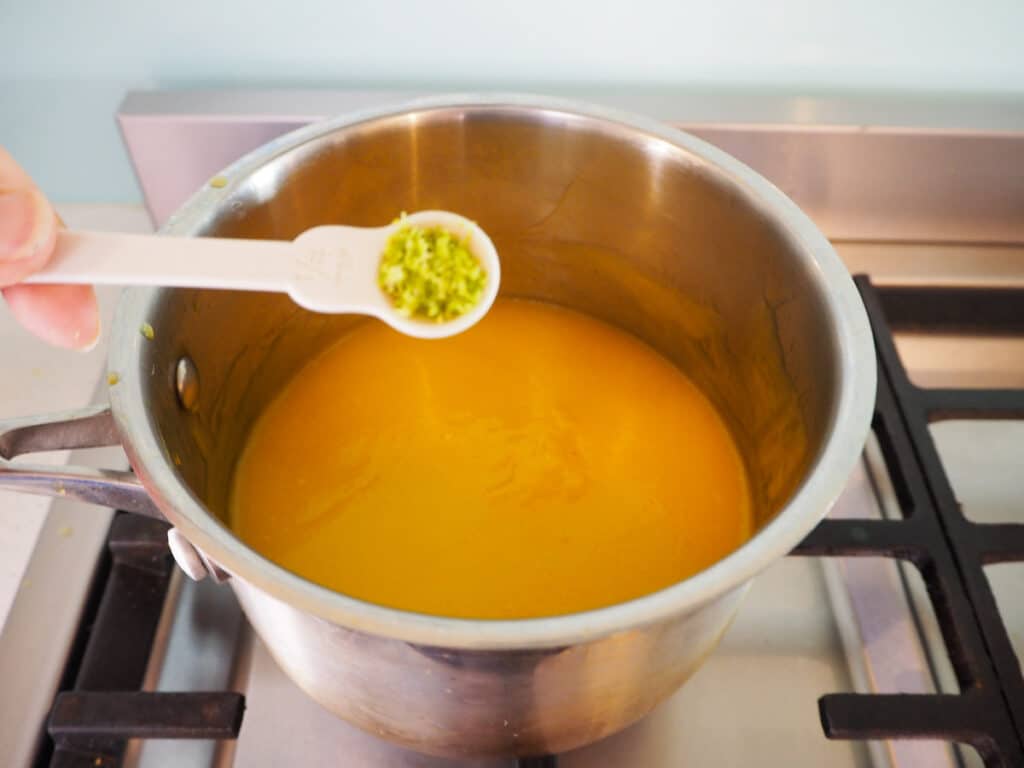 Adding lime zest to mango in pot.