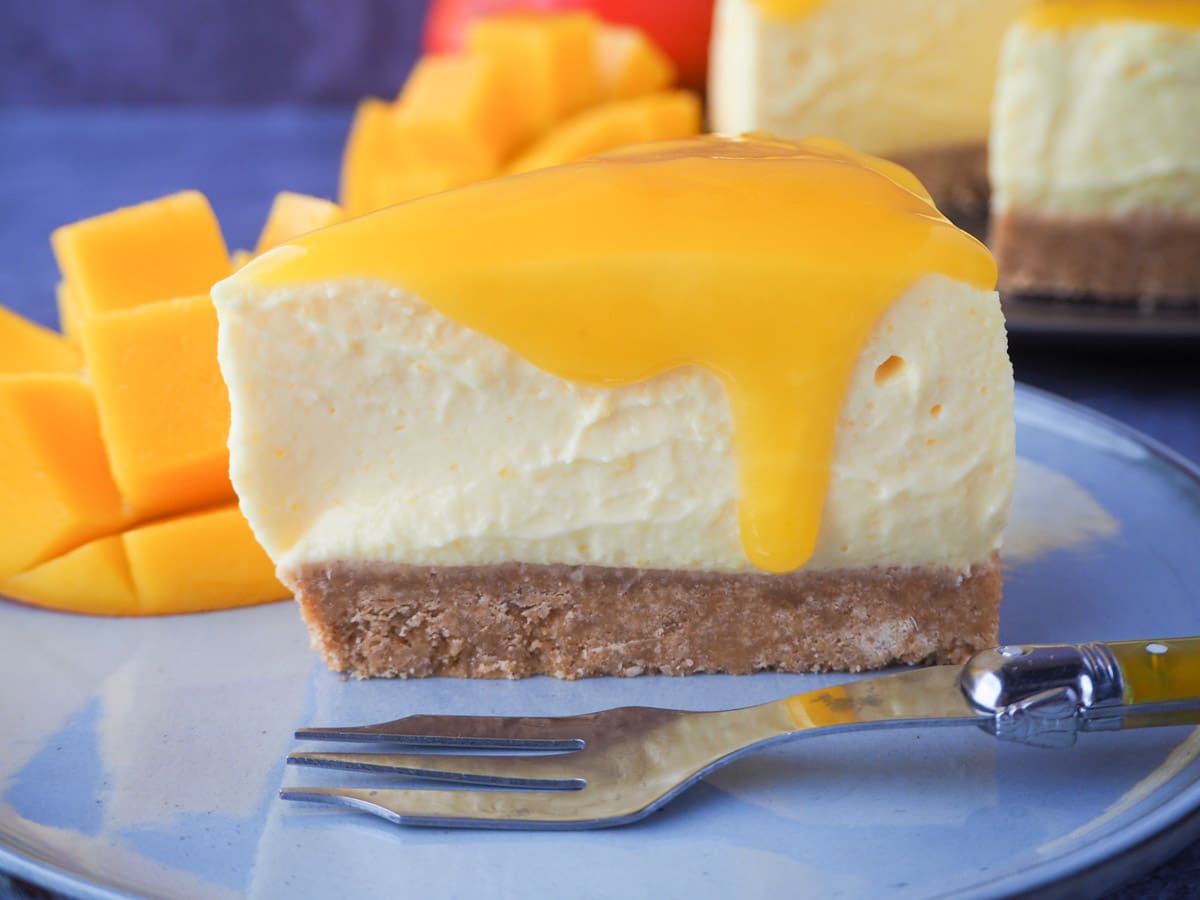 No bake mango cheesecake 22 Slice of no bake mango cheesecake with mango coulis, a vintage fork and fresh mango on the side.