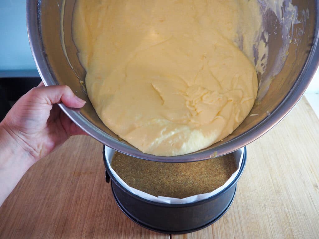 Tipping cheesecake filling over chilled base.