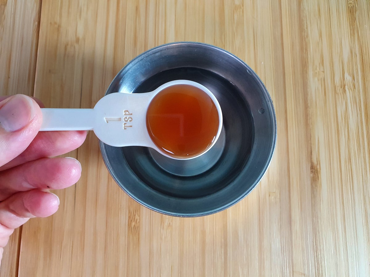 Adding vanilla essence to water in a small bowl.